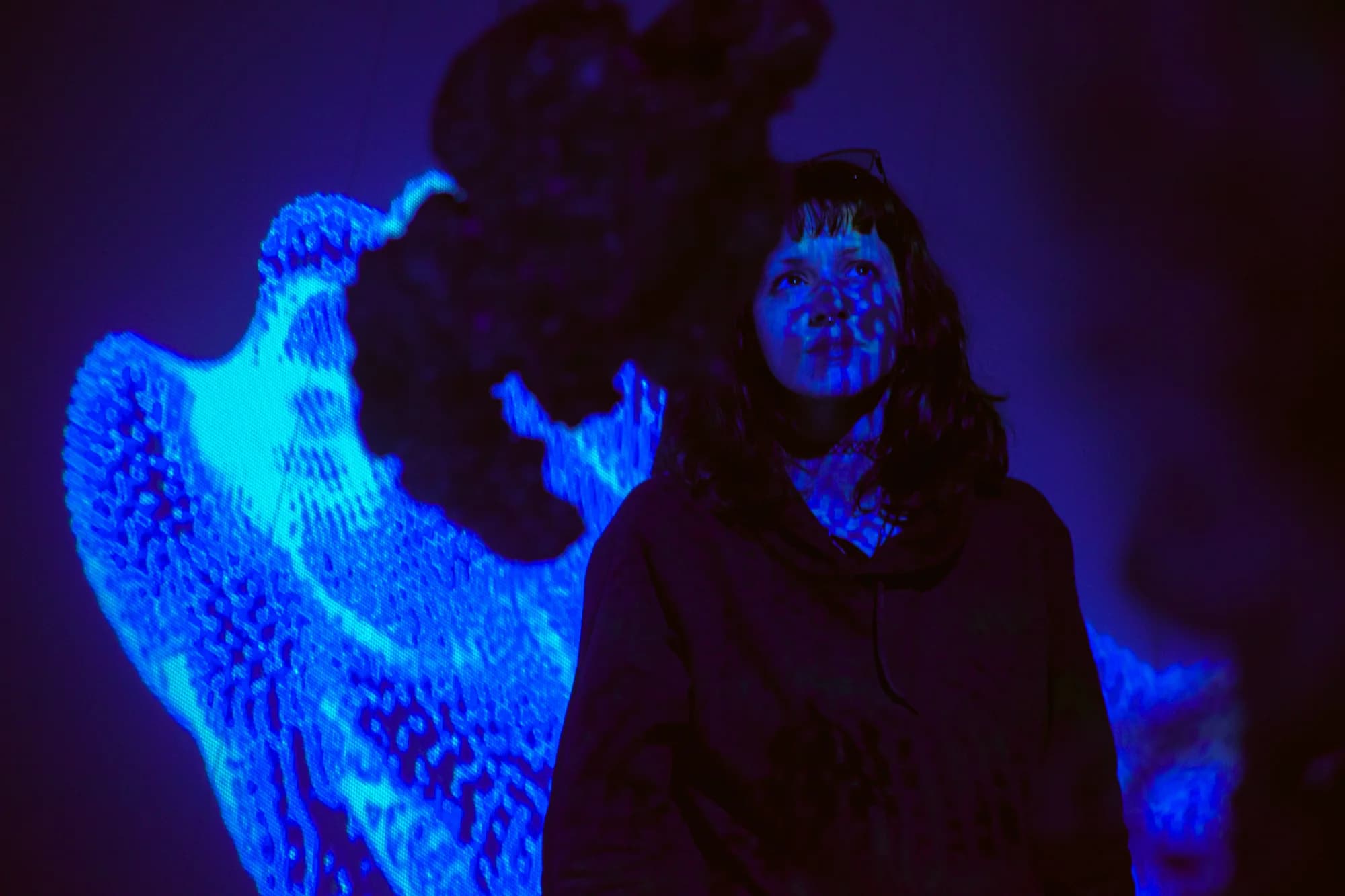 Retrato de visitante entre uma escultura escura e luz azul