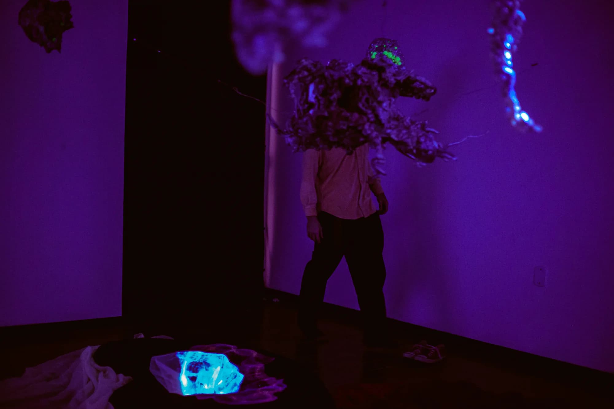 Pessoa atravessa a instalação entre esculturas, projeções e luz violeta